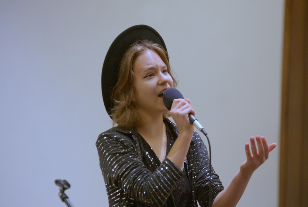 Dziewczynka w wieku około 14 lat, śpiewająca do mikrofonu na białym tle 