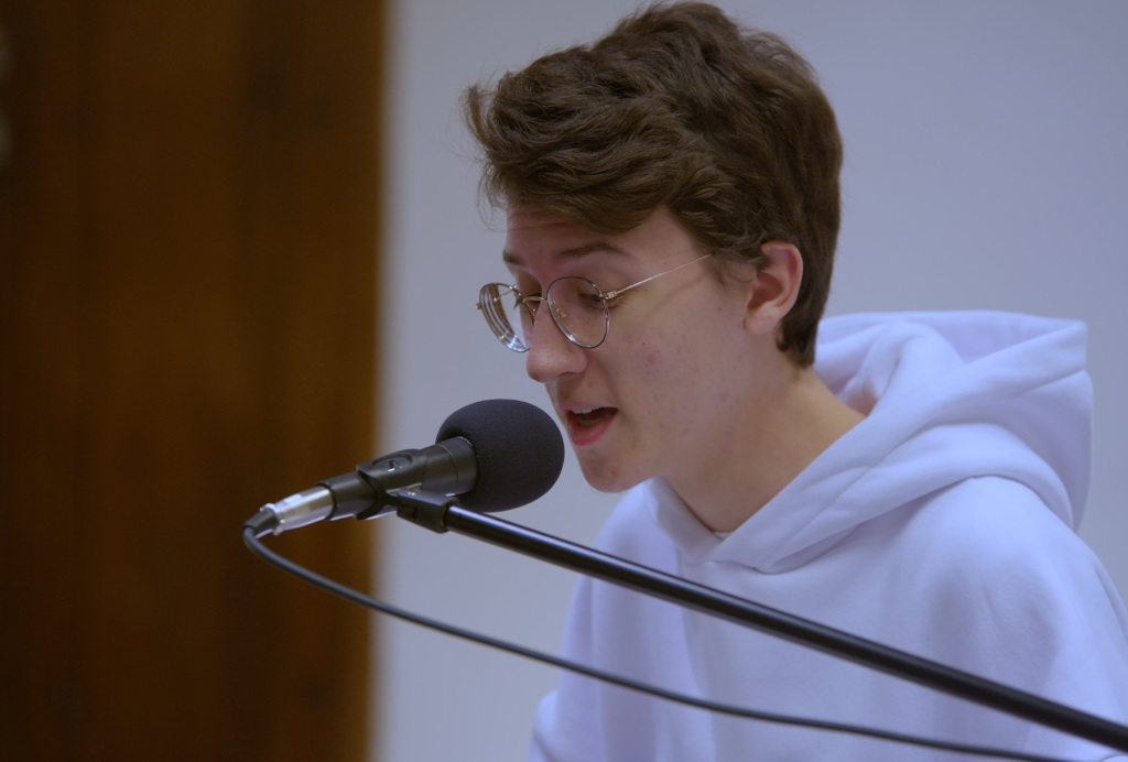 Chłopiec w wieku około 13 lat, śpiewająca do mikrofonu, grający na pianinie 