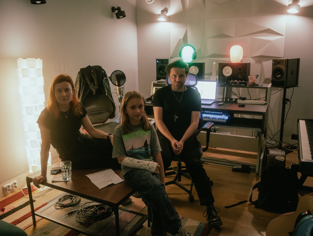 Studio nagraniowe, na pierwszym planie dziewczynka, za nią producent muzyczny oraz kobieta  